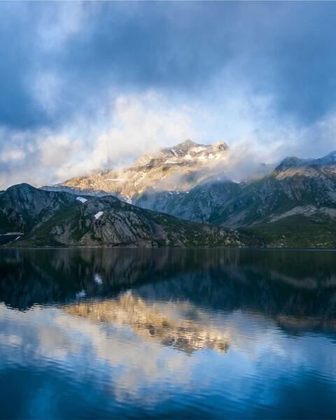 Example to enhance: A mountain peak in clouds mirrored in a lake